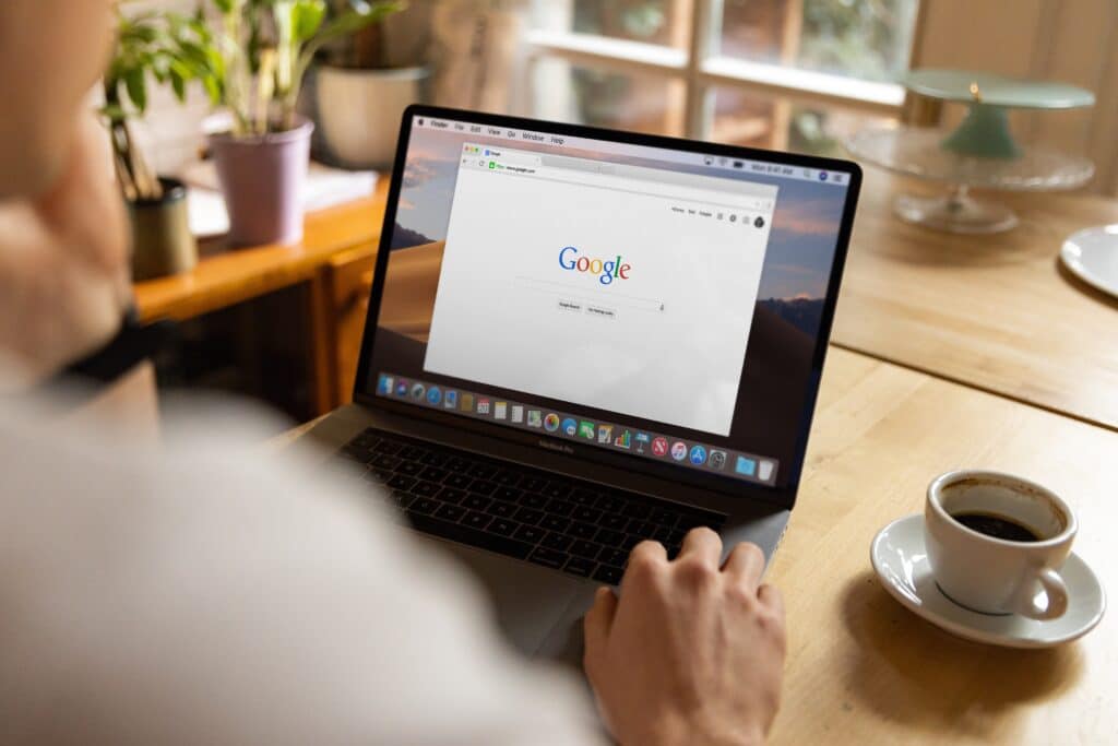 Person sitzt vor dem Laptop und hat den Google Browser offen