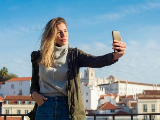 Eine junge Frau nimmt ein Selfie vor dem blauen Himmel auf