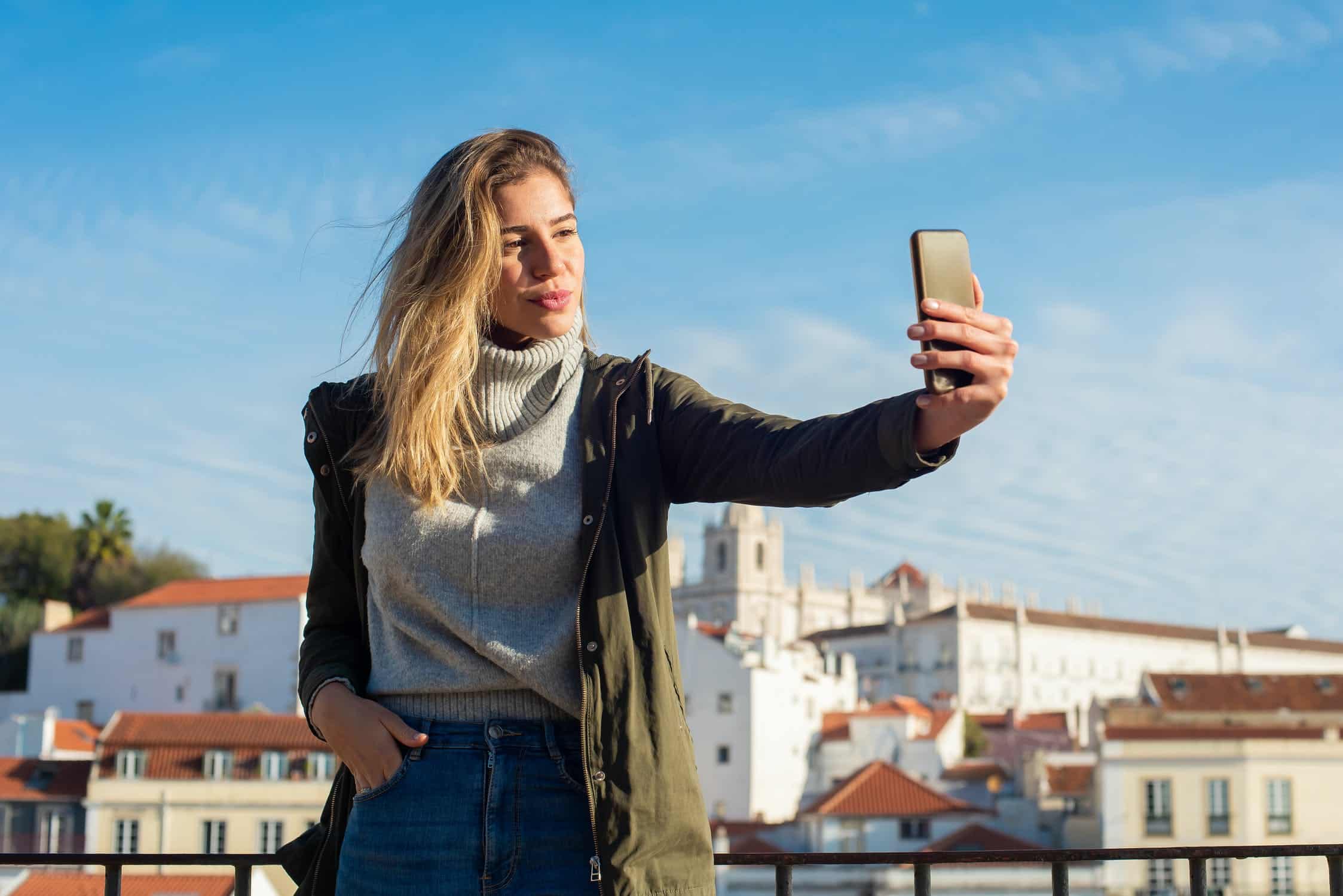 Eine junge Frau nimmt ein Selfie vor dem blauen Himmel auf