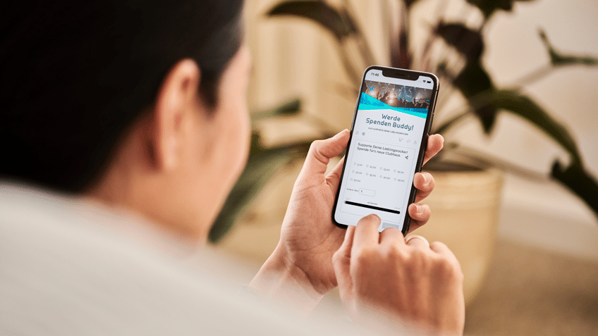 Junger Mann hat am Smartphone die Fundraising-Page seiner Lieblingsrockband geöffnet