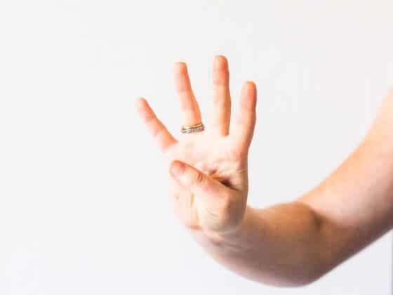 Arm mit Hand vor weißer Hand zeigt vier Finger