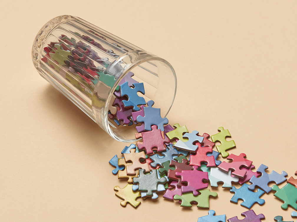 Fallen glass with colorful puzzle pieces as a symbol for the addition of AI with plugins