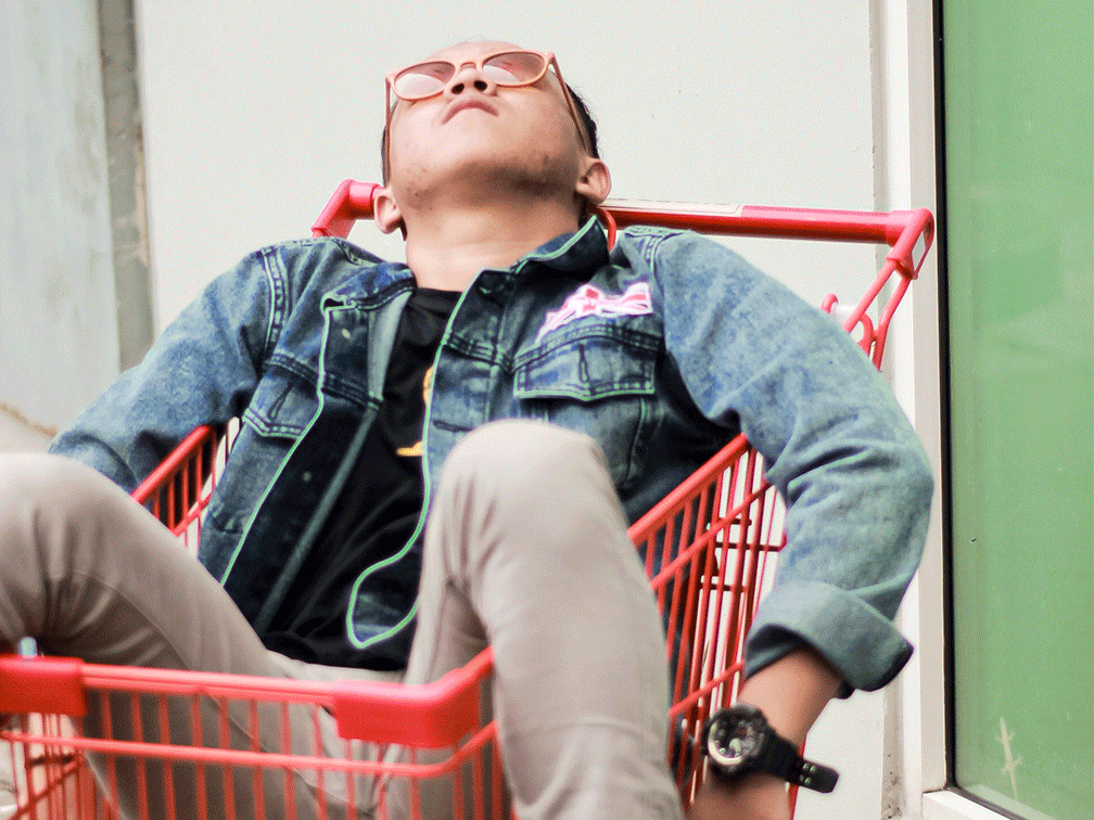 Young men is lying in a red shopping cart
