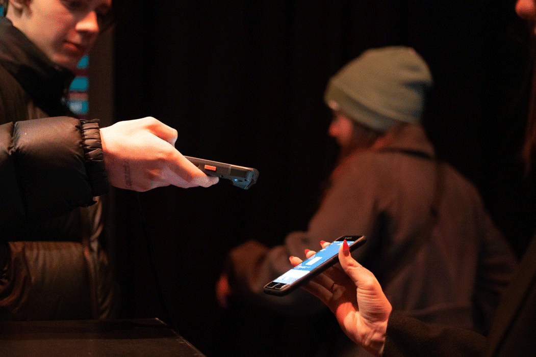 Person scannt am Einlass ein mobiles Ticket ab