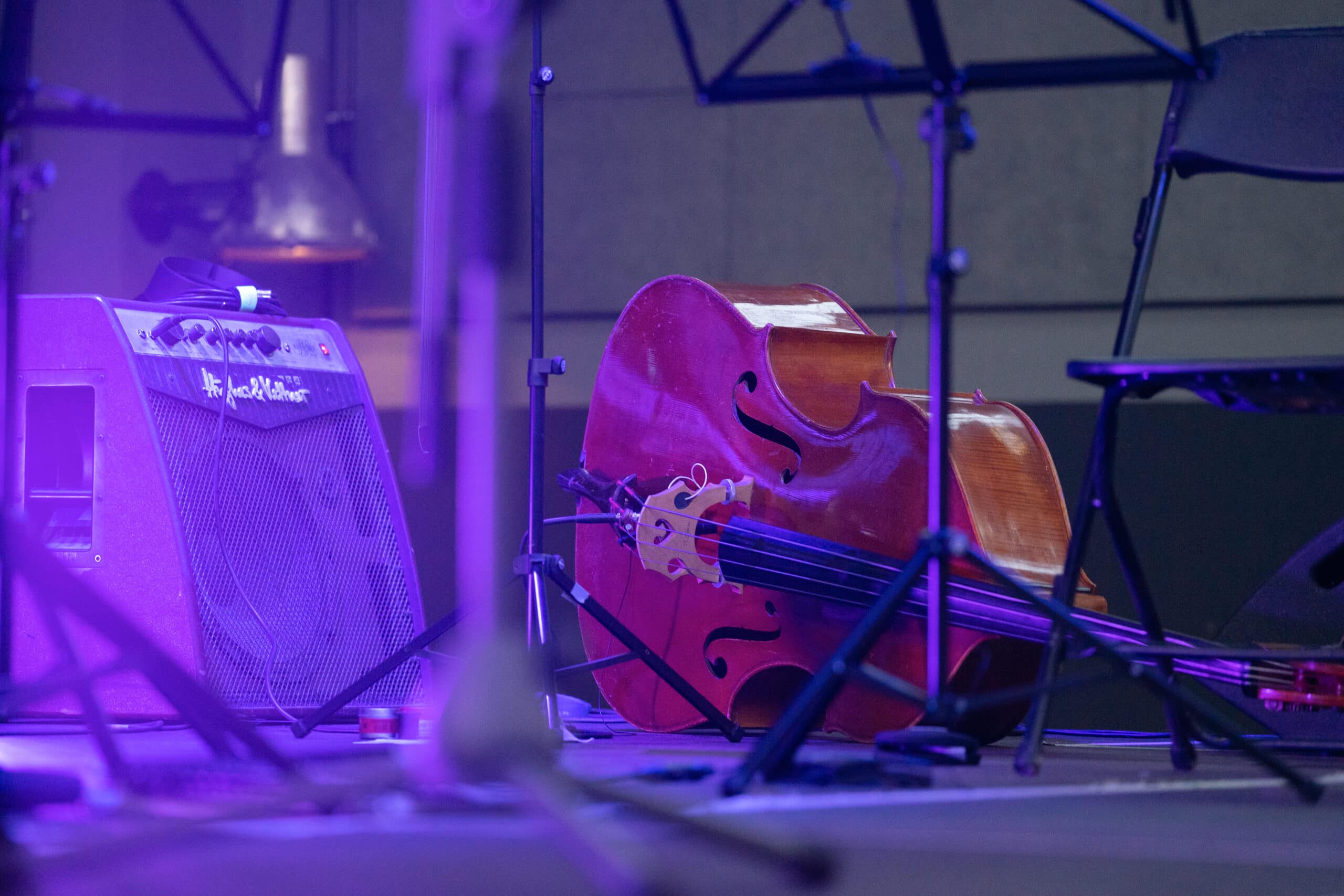 Cello lies on the stage and is illuminated by the violet stage light.